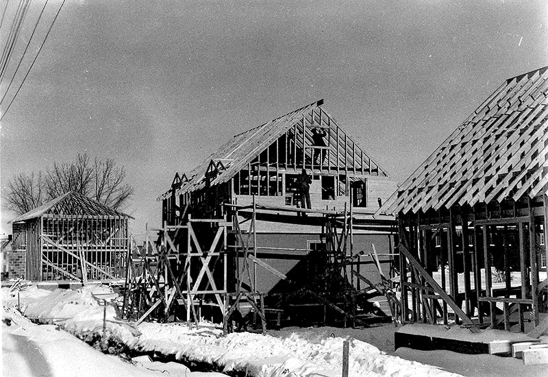 On voit des hommes qui construisent des maisons en hiver.