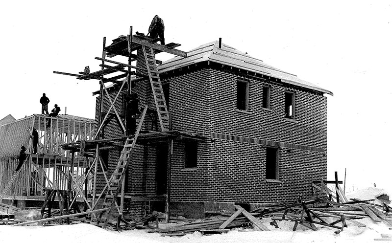 Des menuisiers construisent une maison en briques.