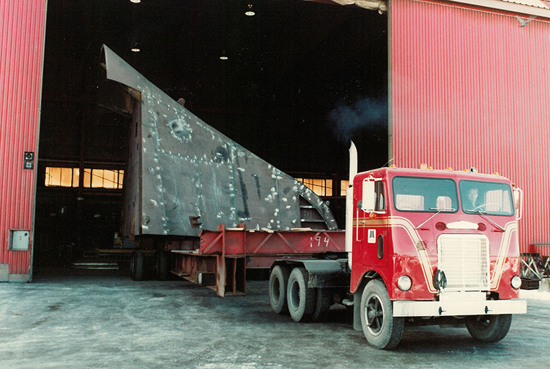 Un homme conduit un camion rouge sur le chantier naval.