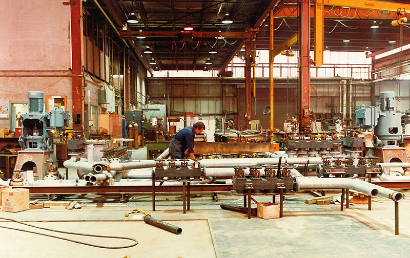 Un homme travaille sur des tuyaux dans un bâtiment du chantier naval.