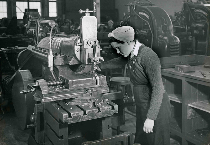 Une femme portant un foulard examine une surface de métal.