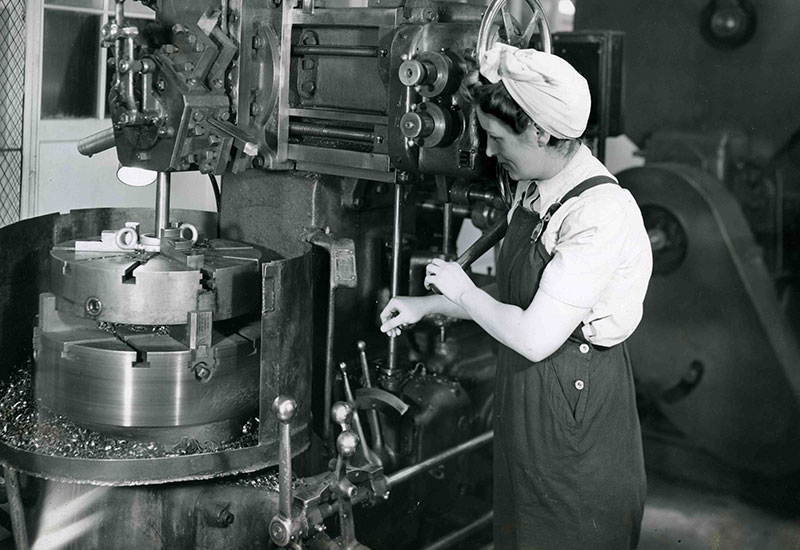 Une femme portant un foulard sur la tête manipule la manivelle d'un appareil.