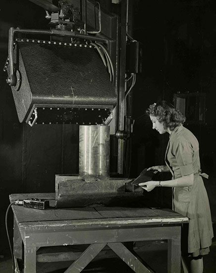 Une femme regarde une plaque de métal.