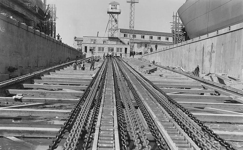 Des travailleurs sont près de la grosse chaîne de la voie ferrée inclinée du chantier naval.