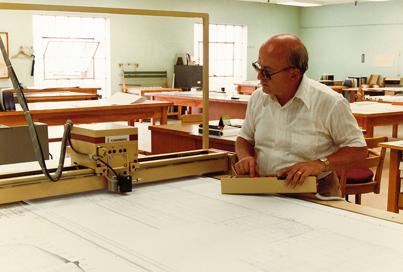 Un homme dessine des plans de navire en atelier.