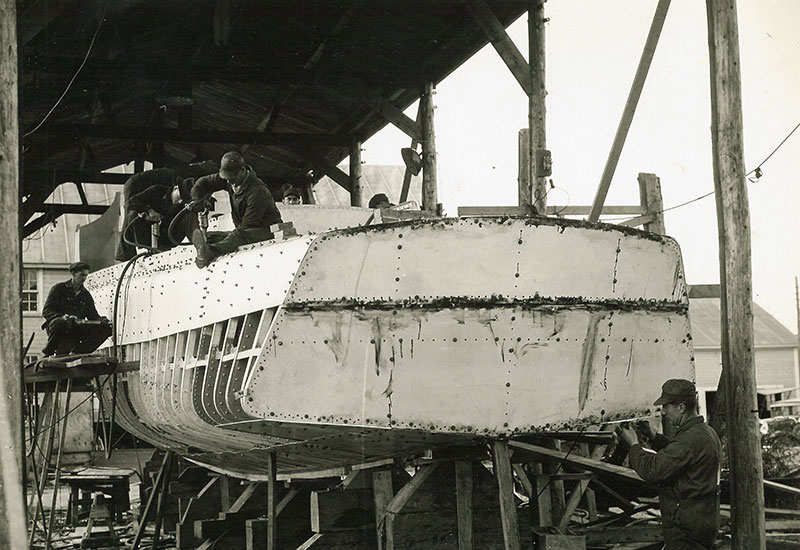 Plusieurs hommes travaillent à la construction du patrouilleur <em>Interceptor</em>.