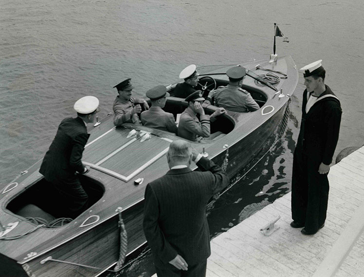Six hommes à bord d'un yacht et deux hommes sur un quai.